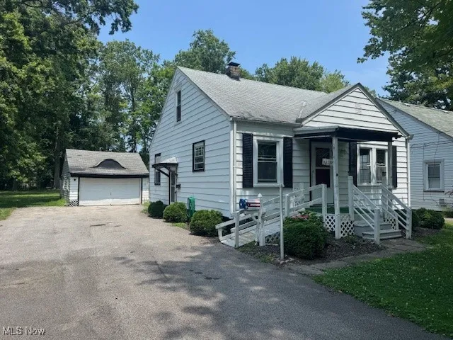 View of front of property with a chimney, an outdoor structure, a detached garage, and a shingled roof