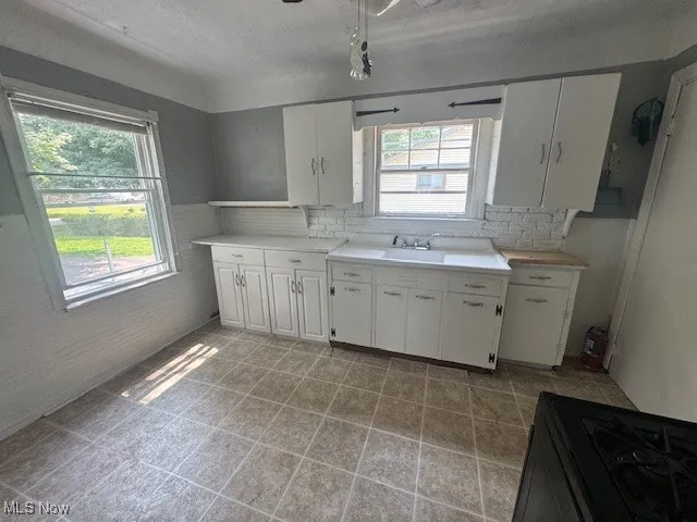 Kitchen featuring plenty of natural light, white cabinets, tasteful backsplash, light countertops, and a textured ceiling