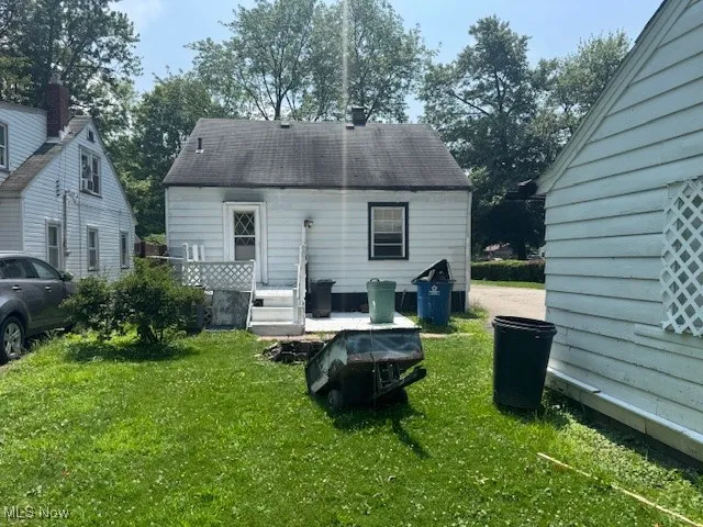 Back of property with a yard and a shingled roof