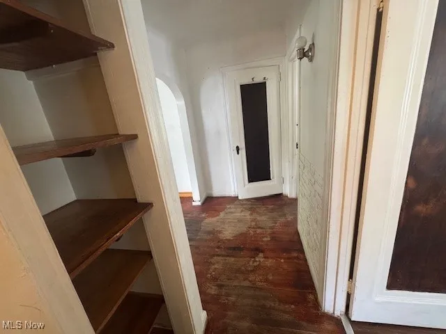 Hallway with dark wood-type flooring and arched walkways