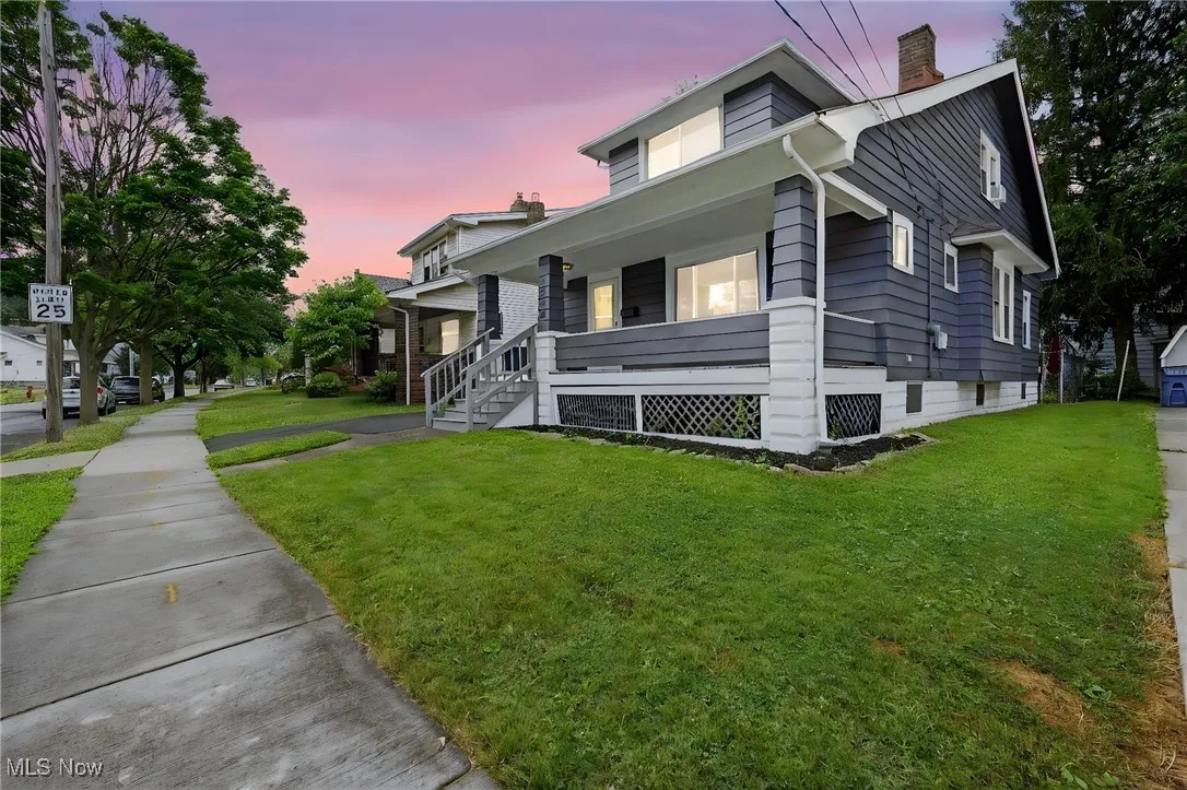 View of front facade featuring covered porch, a chimney, and a front lawn
