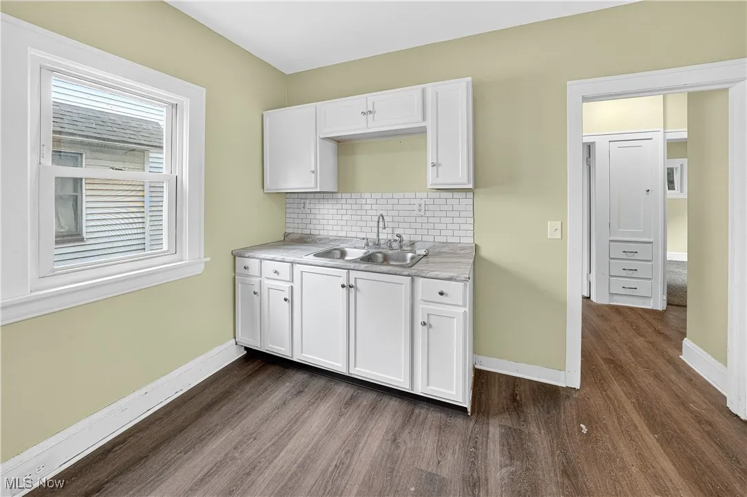 Kitchen with dark wood finished floors, white cabinets, tasteful backsplash, and light countertops