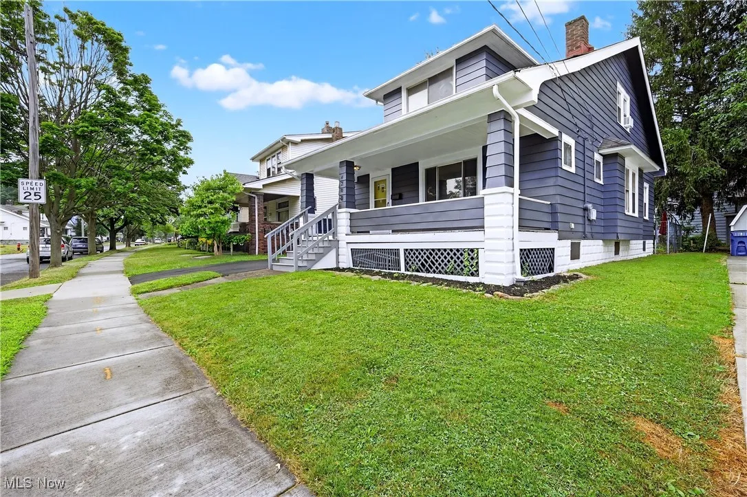 View of front facade featuring covered porch, a chimney, and a front lawn