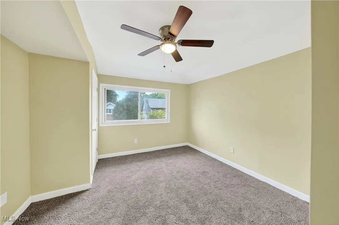 Carpeted empty room with baseboards and a ceiling fan