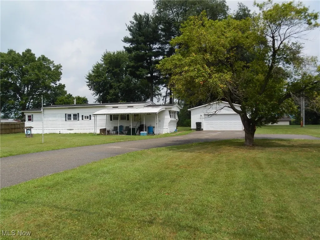 View of front of property featuring a front yard, an outdoor structure, and driveway