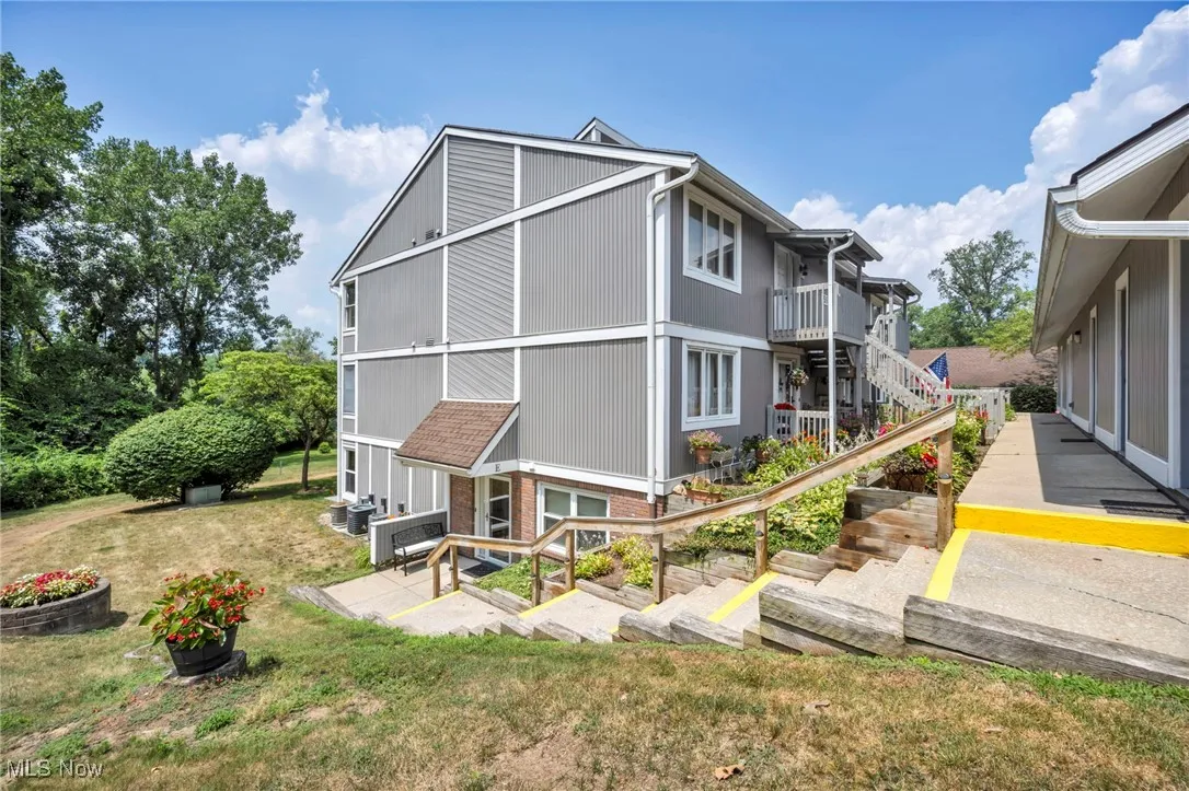 Back of house with a yard, a patio, brick siding, and stairway