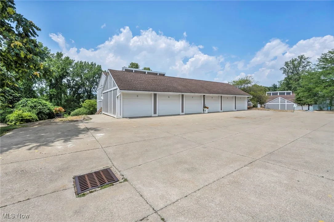 View of property exterior featuring community garages and roof with shingles