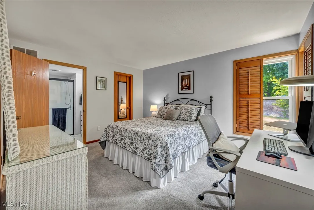 Bedroom with light colored carpet and an office area