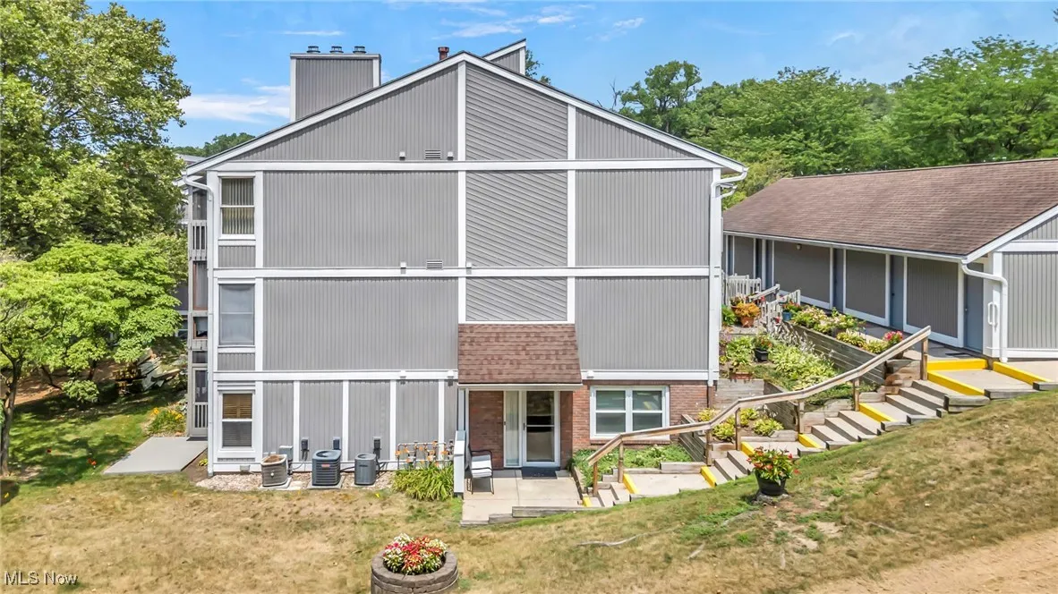 Back of property with a patio area, brick siding, a chimney, and a lawn