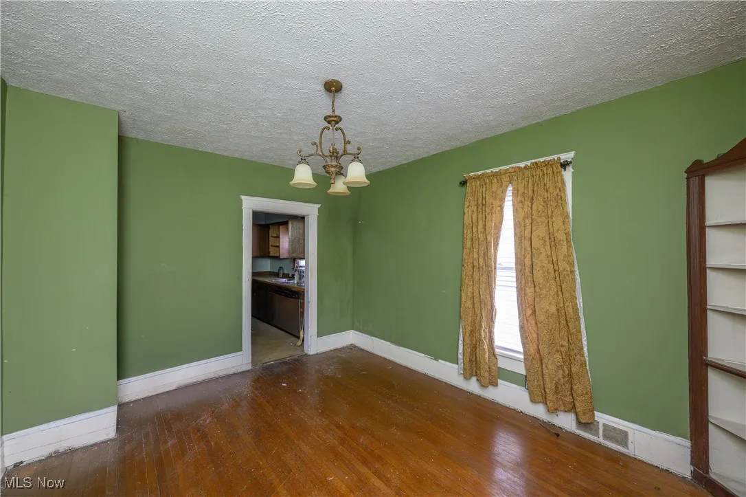 Spare room with a chandelier, wood-type flooring, and a textured ceiling