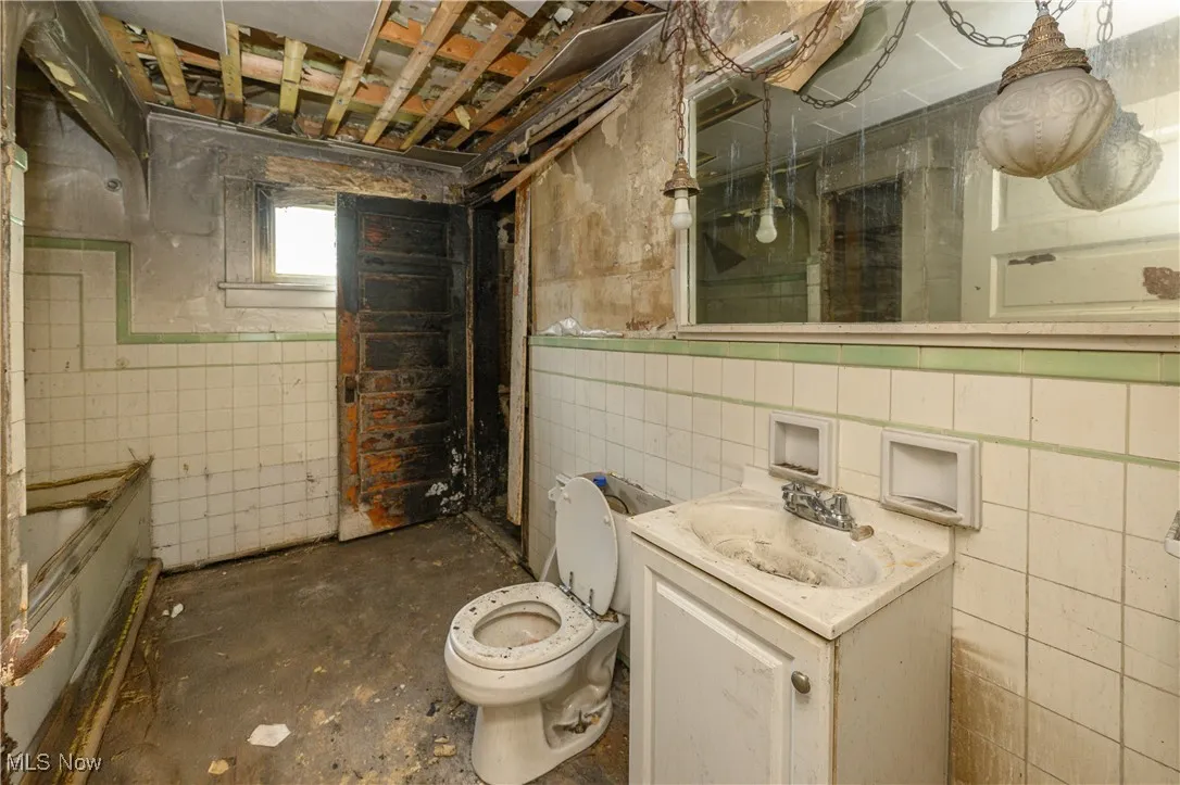 Bathroom with vanity, tile walls, and concrete flooring
