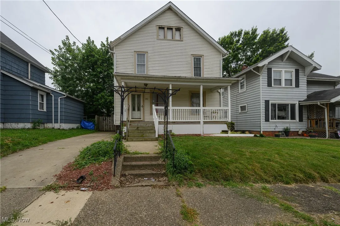 View of front of property with covered porch, a front yard, and concrete driveway