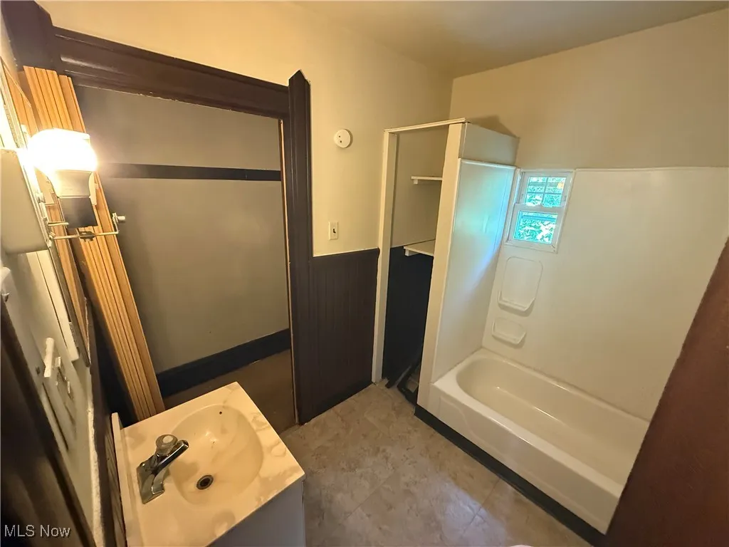 Full bath with vanity, wainscoting, and bathing tub / shower combination