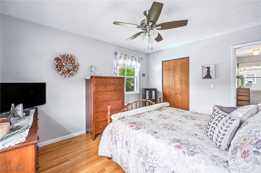 Bedroom with light wood-style floors, multiple windows, a closet, and ceiling fan