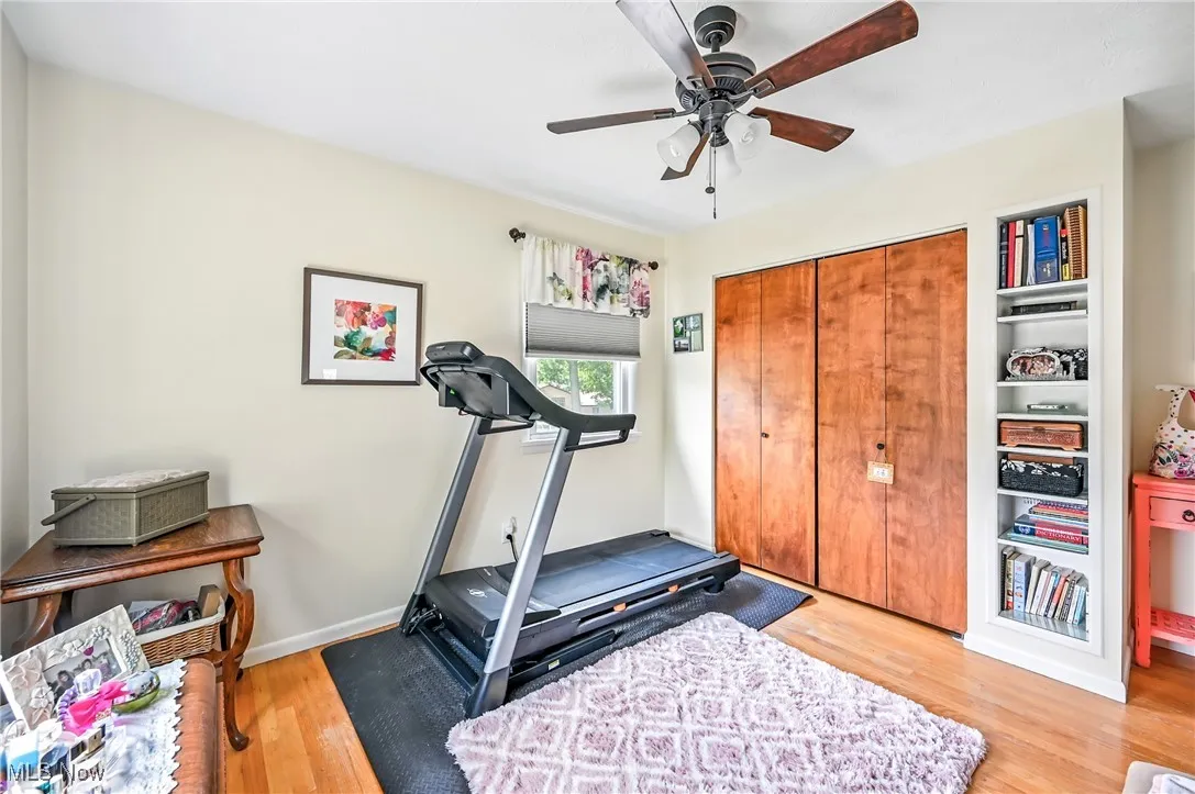 Exercise area with light wood-type flooring and a ceiling fan