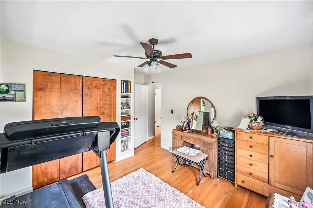 Home office with a ceiling fan, light wood-style floors, and wine cooler