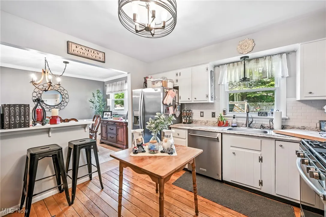 Kitchen featuring appliances with stainless steel finishes, a chandelier, light countertops, white cabinets, and crown molding