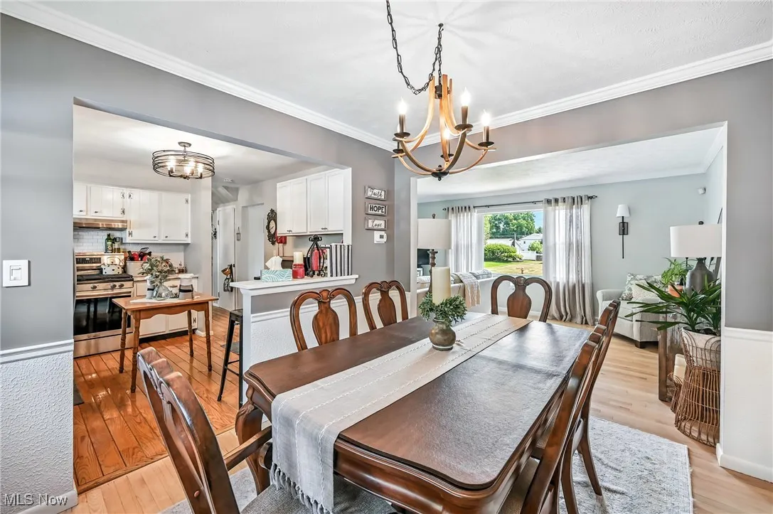 Dining space featuring a chandelier, ornamental molding, and light wood-style flooring
