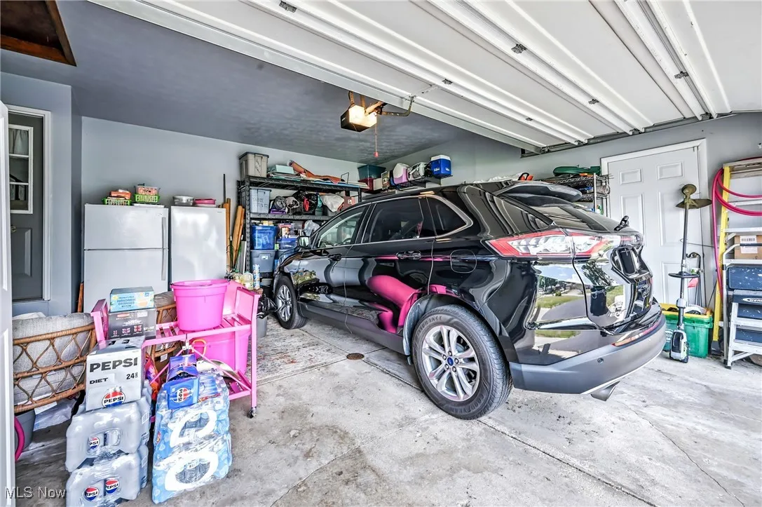 Garage featuring freestanding refrigerator and a garage door opener