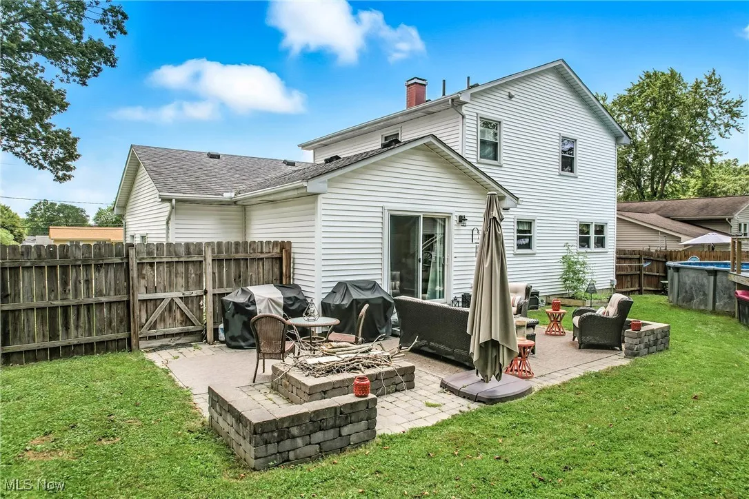 Back of property featuring a chimney, a patio, an outdoor living space with a fire pit, and roof with shingles