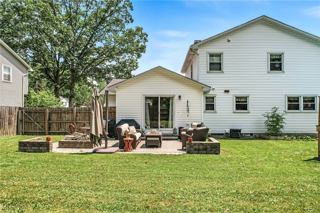 Rear view of property featuring an outdoor living space with a fire pit and a patio area