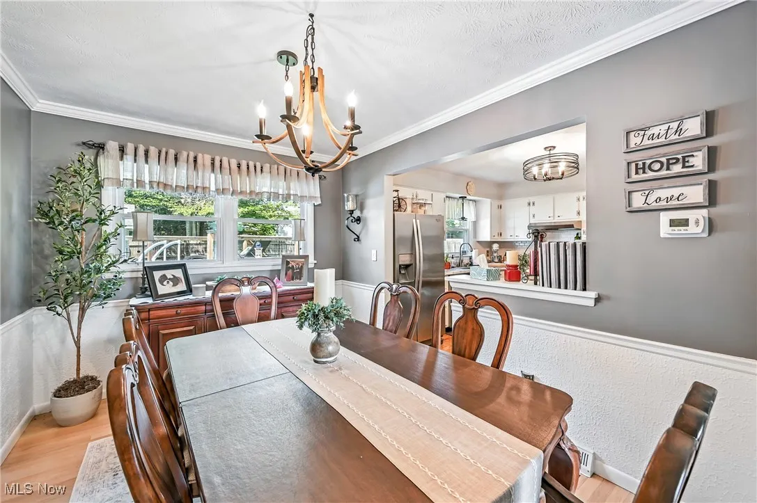 Dining area featuring a chandelier, light wood-style flooring, and molding