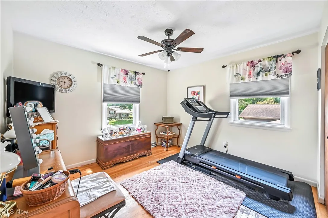Workout room with healthy amount of natural light, wood finished floors, and ceiling fan