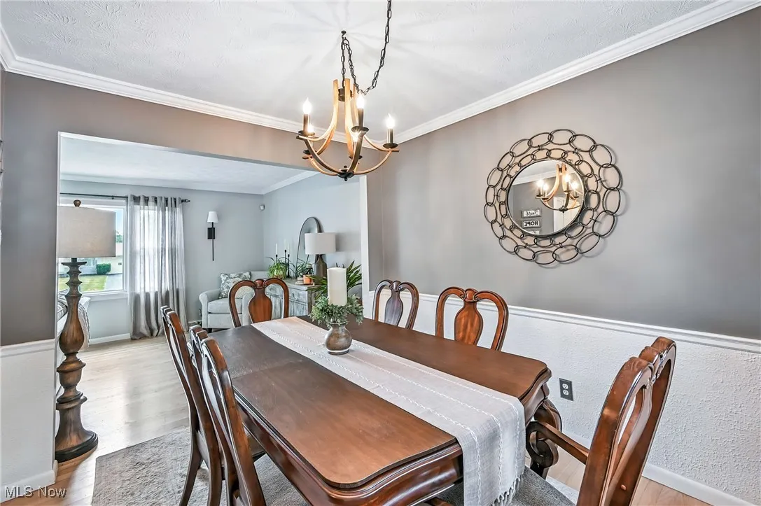 Dining room with crown molding, a chandelier, and light wood-style floors