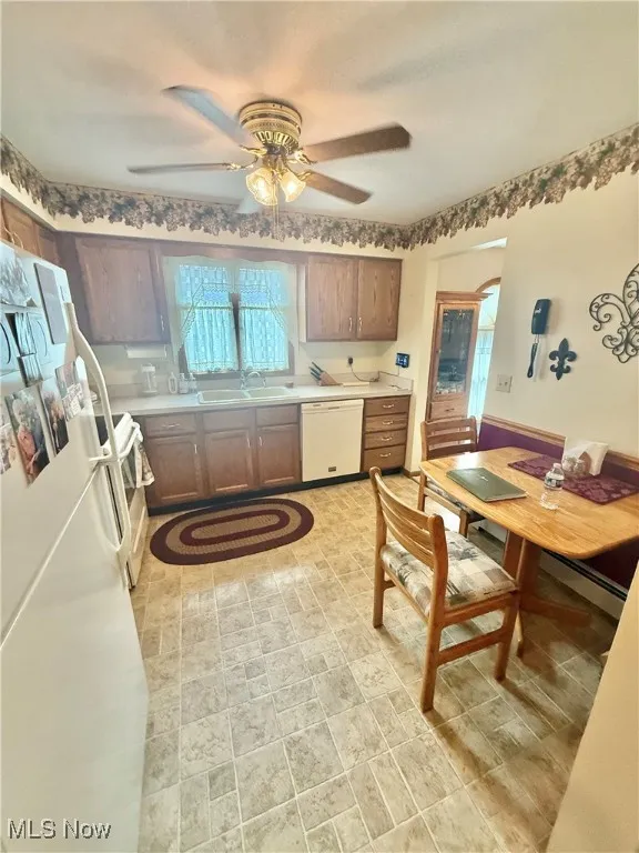 Kitchen with white appliances, ceiling fan, and light countertops