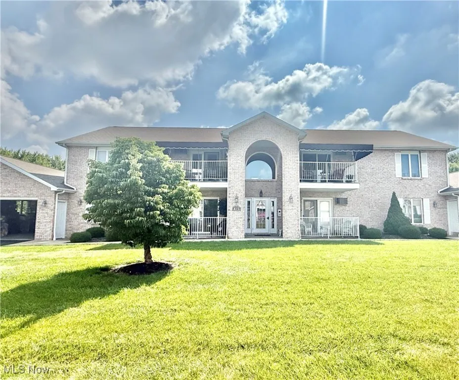 Traditional home featuring brick siding, a balcony, and a front yard