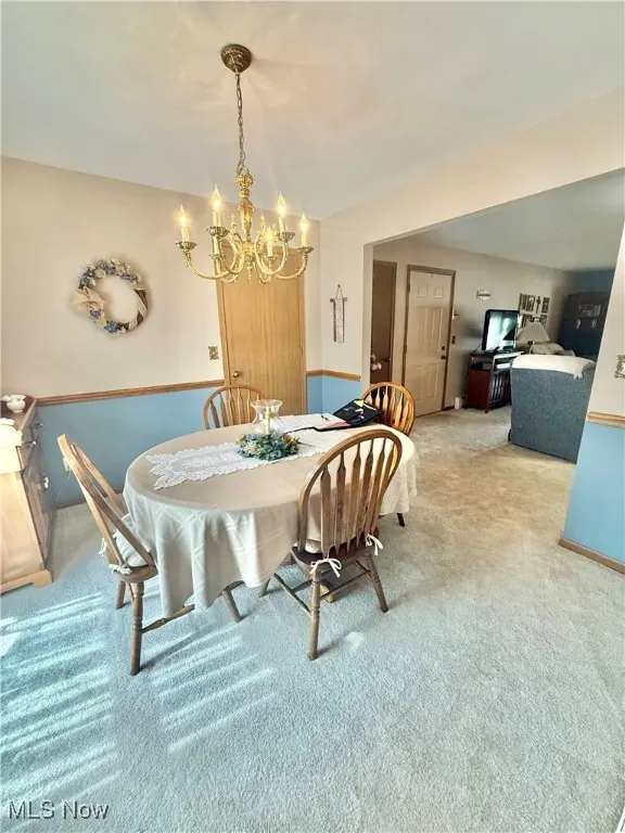 Dining area featuring light colored carpet and a chandelier