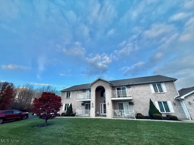 Traditional home with a front lawn, brick siding, and a balcony