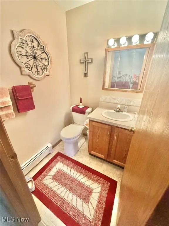 Half bath featuring a baseboard heating unit and vanity