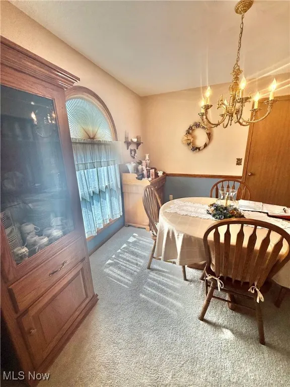 Carpeted dining area with a chandelier