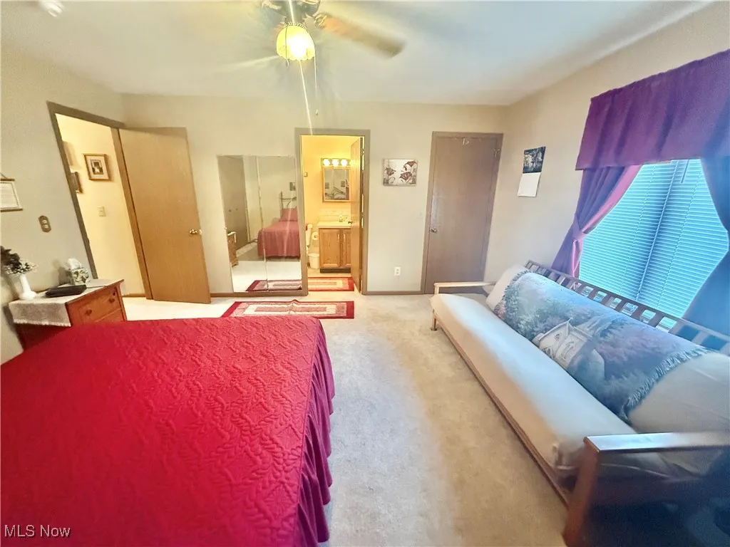 Bedroom featuring carpet, ensuite bath, and ceiling fan