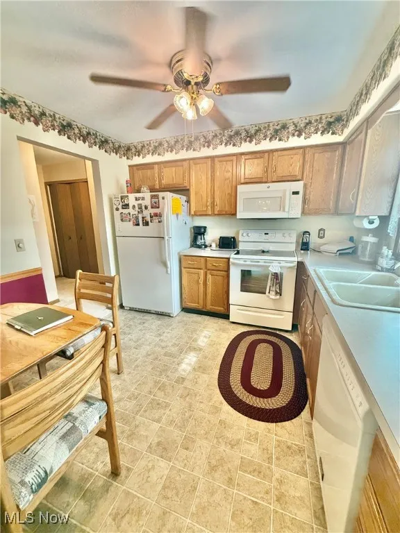 Kitchen with white appliances, light countertops, a ceiling fan, and brown cabinets
