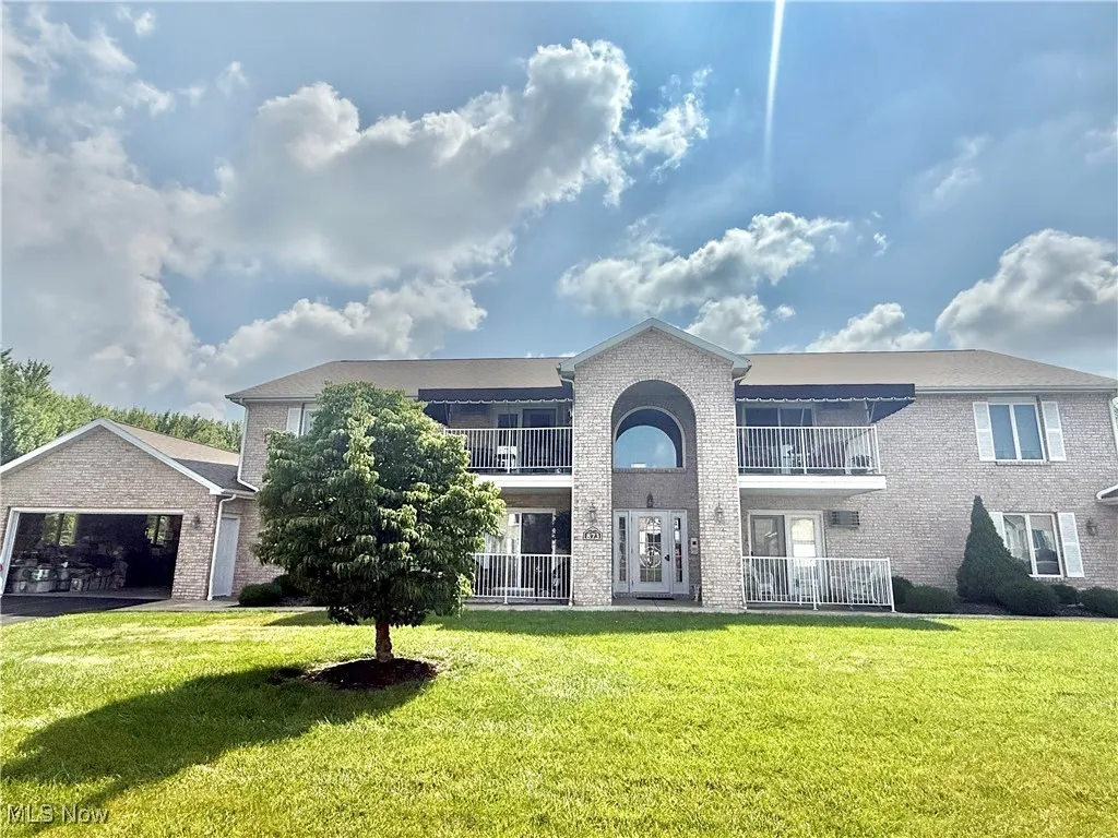 Traditional-style home with brick siding, a balcony, a front yard, and a garage