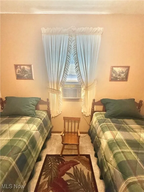Carpeted bedroom featuring cooling unit and baseboards