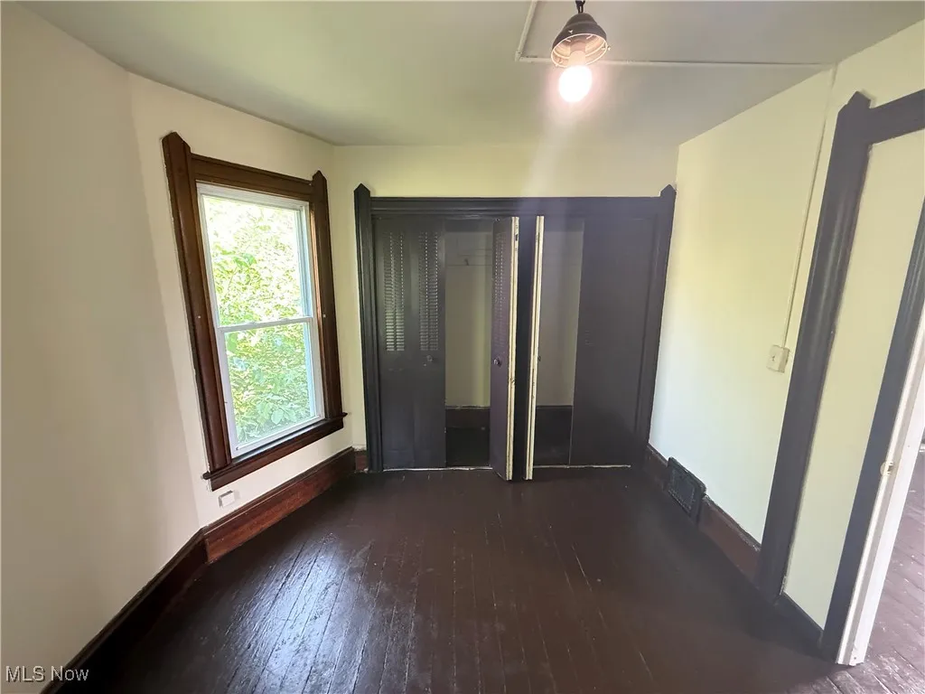 Unfurnished bedroom featuring wood-type flooring and baseboards