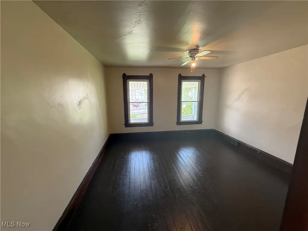 Empty room with dark wood-type flooring and ceiling fan