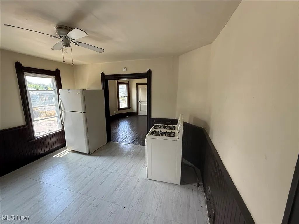 Kitchen with white appliances, wainscoting, and ceiling fan