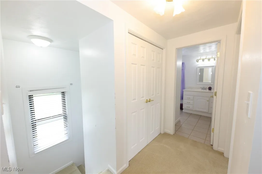 Hall featuring light carpet and light tile patterned floors