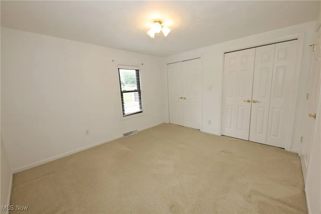 Unfurnished bedroom featuring two closets and light colored carpet