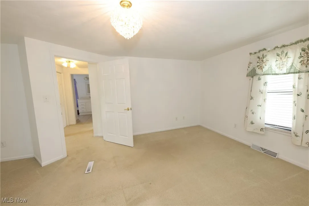 Empty room with light carpet and a chandelier