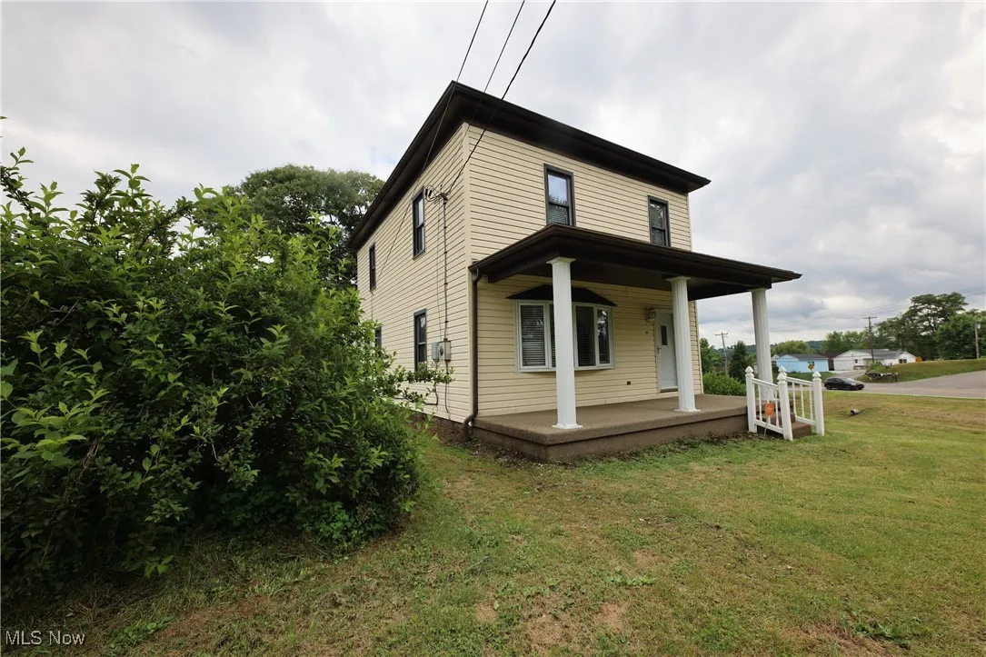 View of home's exterior with a porch and a yard