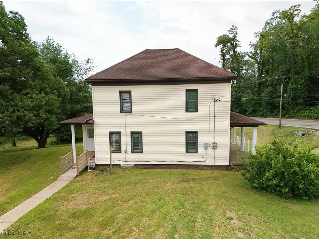 Back of property with a lawn and a shingled roof