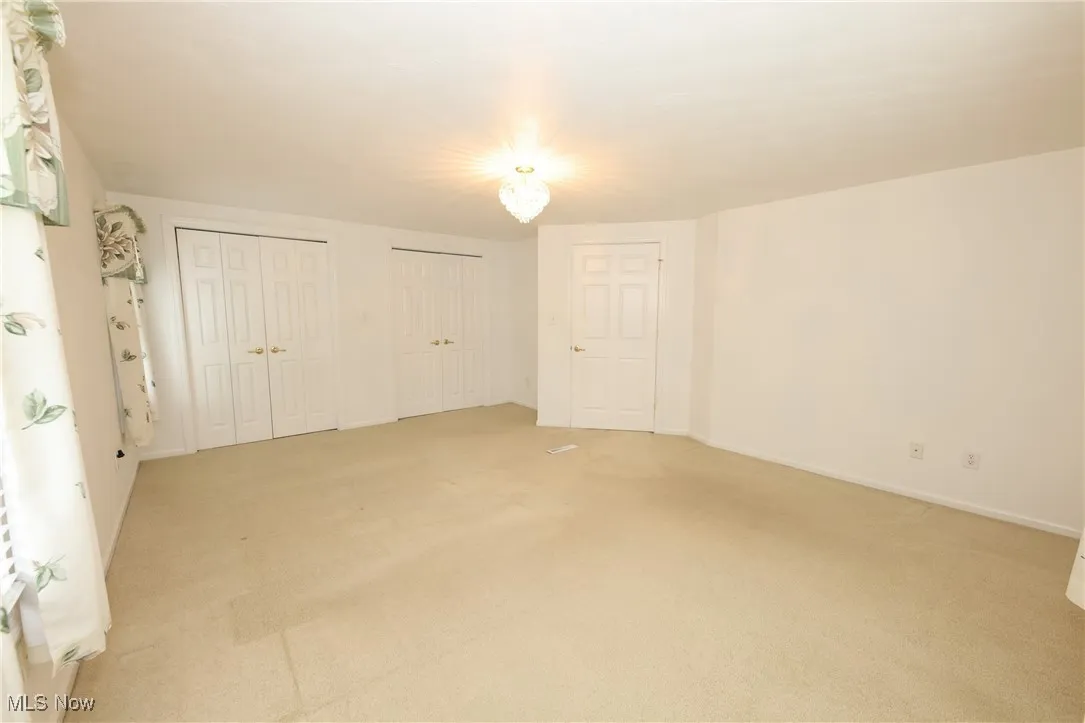 Unfurnished bedroom featuring light colored carpet and two closets