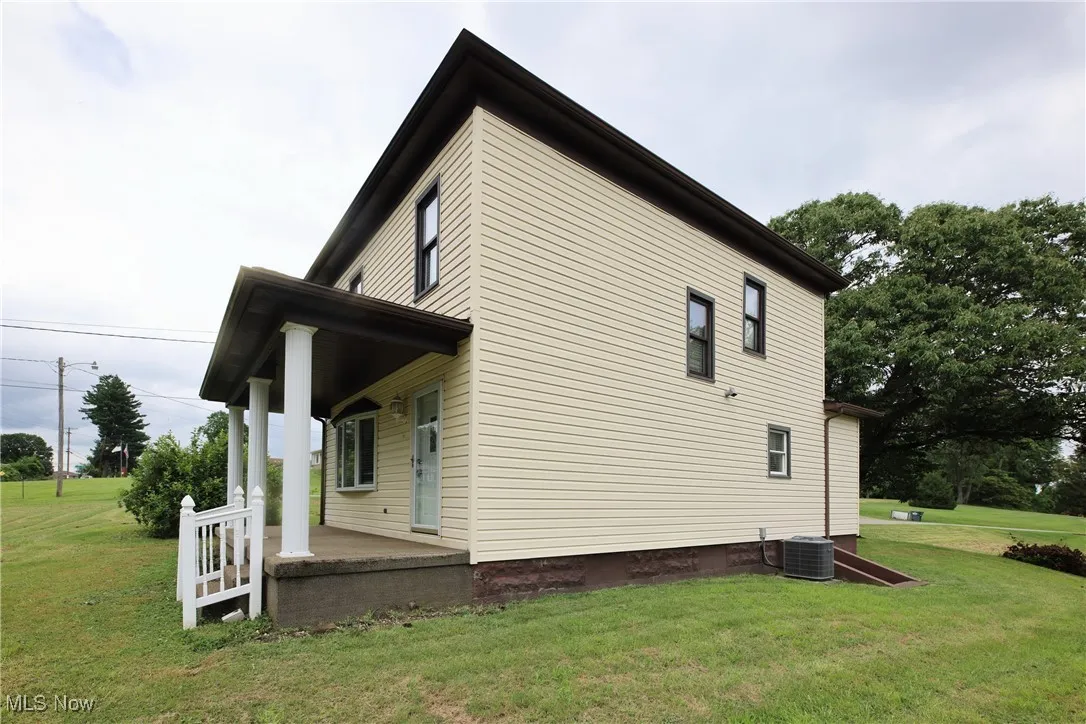 View of home's exterior with covered porch and a lawn