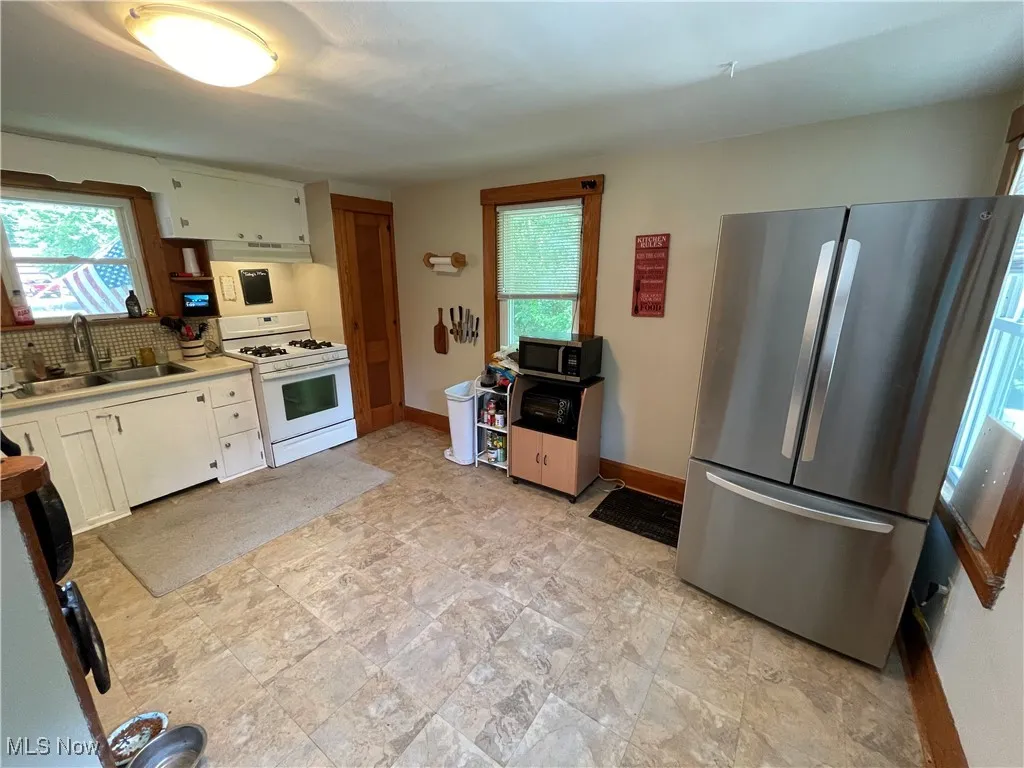 Kitchen featuring appliances with stainless steel finishes, under cabinet range hood, plenty of natural light, and tasteful backsplash