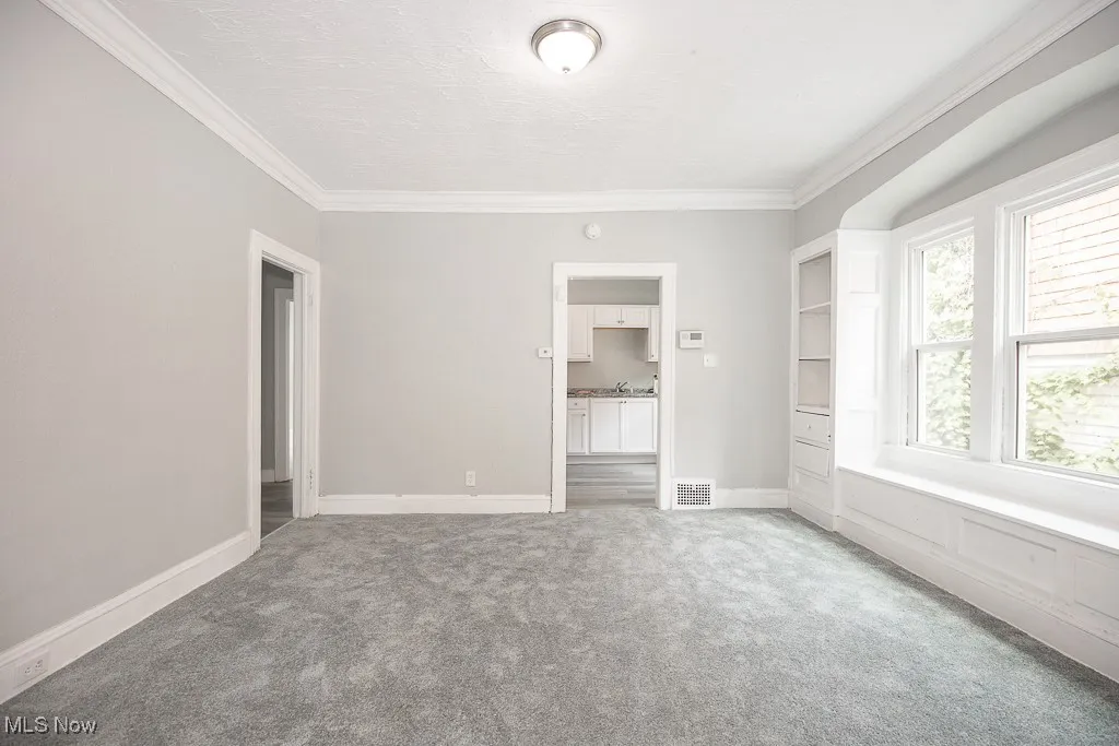 Unfurnished room featuring light colored carpet and ornamental molding